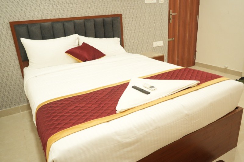 Made-up double bed with burgundy runner in the Executive Deluxe room